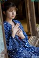 A woman in a blue and white kimono sitting on a porch.